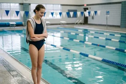Adolescente timide au bord d'une piscine intérieure prête à surmonter ses craintes grâce à la natation