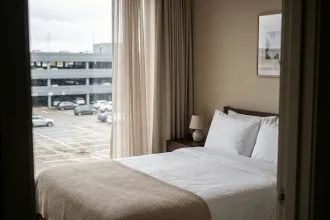 Chambre d'hôtel avec vue sur un parking en béton gris depuis la fenêtre